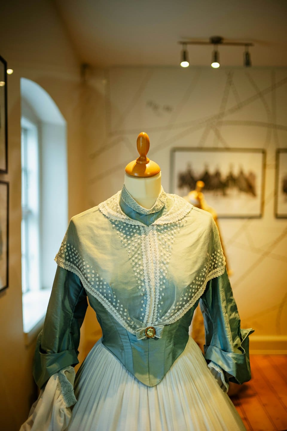 Abito storico in pizzo blu petrolio e bianco su un manichino.