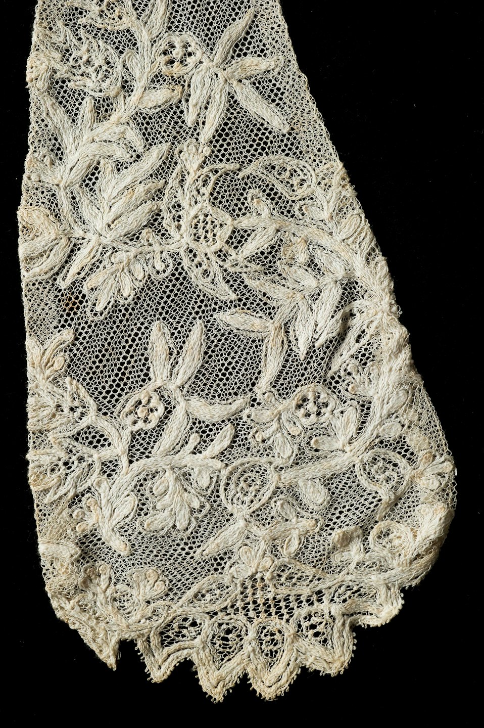 Pizzo bianco antico dettagliato con motivi floreali su tessuto nero.