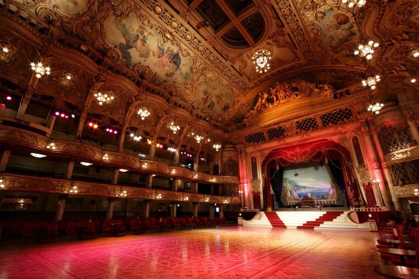 Sala da ballo vuota e ornata con architettura dorata e tende di velluto.